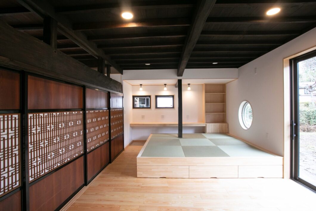 塩尻市の古民家を現代風にリノベーションした小上がりの畳スペース。再利用された建具と黒梁が趣を演出。